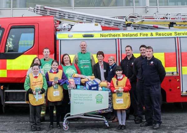 Maria O'Prey, Tesco Newtownabbey Community Champion, trolley dash participants Chris Turley from Glengormley Fire Station and Noel McKee from Whitla Street Fire Station with Tesco staff, firefighters from Glengormley Fire Station and pupils from St MacNissi's Primary School who helped with the Foodbank collection at Tesco, Abbey Retail Park. INNT 49-516-SO