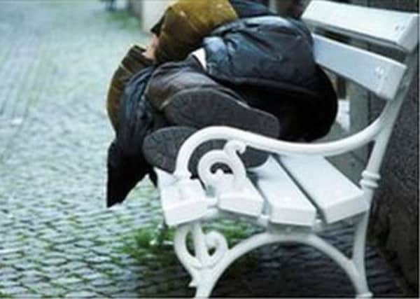 A homeless person sleeping on a bench