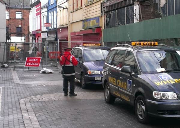 A traffic attendant issuing parking notices to two taxis on Dunluce Street.  INLT 52-682-CON