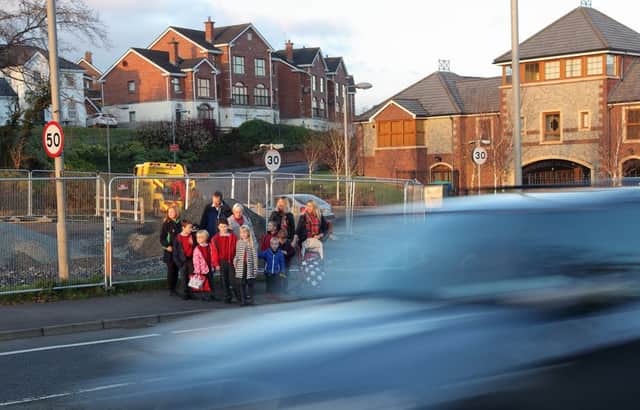 Parents and children from the Linen Green housing development wait to cross a busy road on their way to Pond Park Primary School. US1447-546cd  Picture: Cliff Donaldson