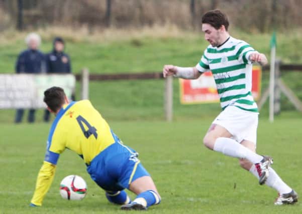 Lurgan Celtic's Josh Barton goes to skip over the challenge of his Bangor opponent. INLM02-674AM