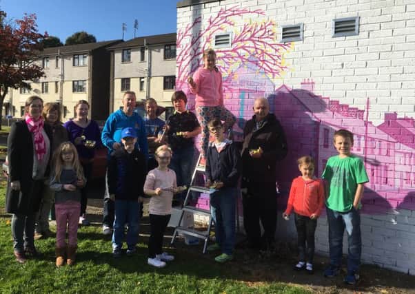 Housing Executive local manager Breige Mullaghan (far left) beside artist Louie Winward, Castle Community Association members, Dessie Hanna (right) and Martin Neill (middle) with budding young artists from the local area.
