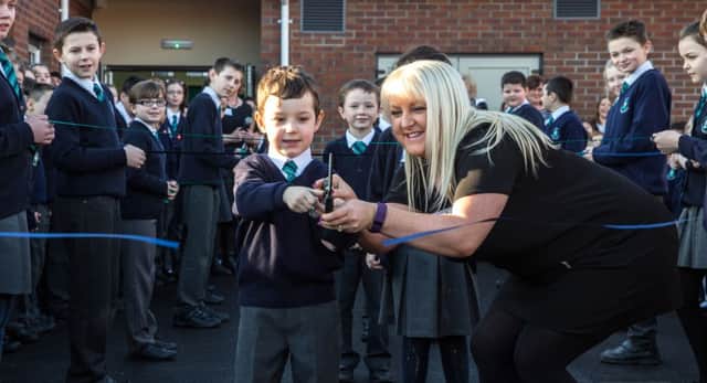 Primary one pupil Josh, helped by teacher Danielle Barnes, cuts a ribbon to officially open the new extension at Acorn Integrated Primary School. Pic by Mark Barnes Photography INCT 04-751-CON