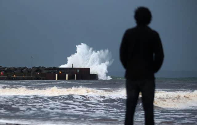 vMcAuley Multimedia 01/02/15 Storm Henry brews. Walkers on Ballycastle Beach stop for a photograph as wind speeds reach 80mph on the North Coast, Storm Henry is expected to batter the UK the next over the next number of hours. Pic Steven McAuley/McAuley Multimedia