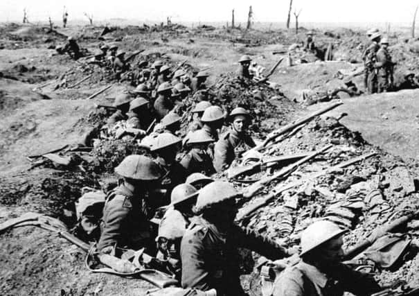Infantrymen occupying a shallow trench in a ruined landscape before an advance during the Battle of the Somme