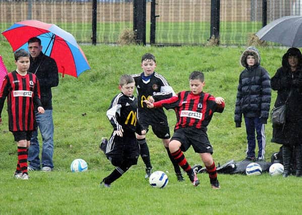 Carniny Youth U-13s and their Antrim Rovers counterparts battle for possession as spectators take shelter from the wet conditions at Ballykeel. INBT 09-812H
