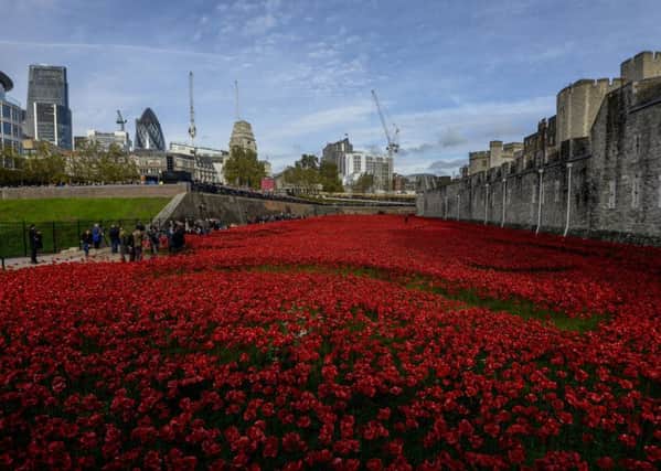 Visitors on Armistice Day 2014 examine the art installation 'Blood Swept Lands and Seas of Red' by artist Paul Cummins at the Tower of London, marking the centenary of the First World War. PRESS ASSOCIATION Photo.  Photo credit: Andrew Matthews/PA Wire