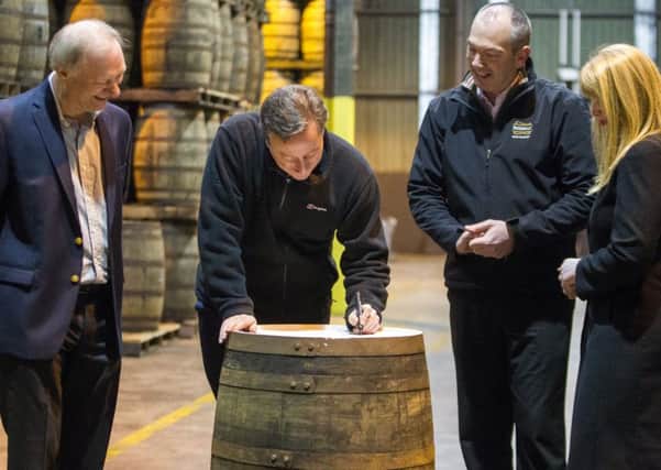Prime Minister David Cameron signs a Bushmills Distillery whiskey barrel that will be sealed for 21 years as Chairman David Gosnell (left) looks on with Manager of the Distillery Colum Egan & Technical manager Helen Mulholland (right) during his visit to Bushmills distillery in Co Antrim as he continues a tour of the UK setting out the case for staying in the European Union. Photo: Liam McBurney/PA Wire