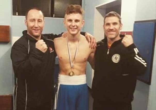 Leon Young clebrates his County Antrim Championships success alongside two proud Lisburn Boxing Club coaches.