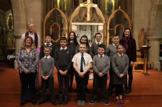 Primary 7 pupils celebrating their Service of Light with An tAthair Alan and their teacher.