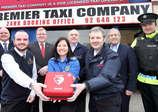 Neil Fyfe, manager of Premier Taxis, Yvonne Craig, NI Ambulance Service, and Steven Hall, NI Fire Service, with a defibrillator which will be available at the taxi company, at Smithfield Square, Lisburn, as part of its role as a base for dealing with emergencies. Looking on (back row) are Lesley Haslen, Premier Taxis supervisor, Stephen McKee, Premier Taxis day shift supervisor, Jonathan Craig MLA, Adie Bird, director of Resurgam Trust, Martin Busch, vice chair of PCSP, and Inspector Nigel Rowland, PSNI. Picture: Cliff Donaldson