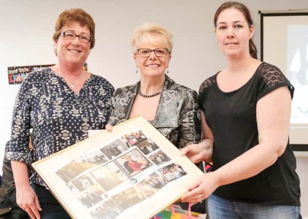 Bea Ogilvie, session supervisor (left), and Kerryanne Hunter, adviser (right), present Pat Hutchinson with a special memento to mark her 32 years of service with Newtownabbey CAB. INNT 14-514-SO