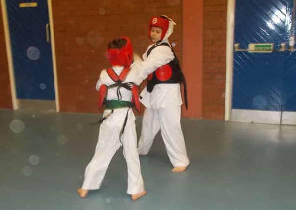 Young members of Seven Towers Karate Club sparring, fully equipped with protective training gear.