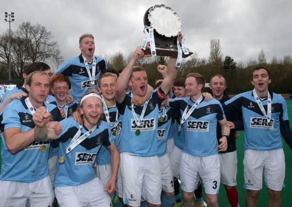 Lisnagarvey's captain Jonathan Bell holds the shield aloft and celebrates with the team after defeating Banbridge.