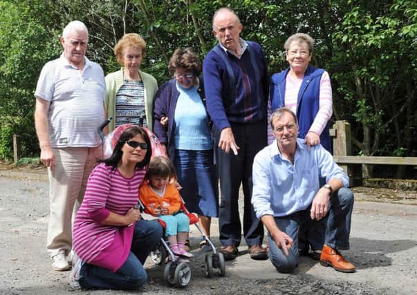 Curran Terrace residents, pictured in 2009, with one of the huge potholes affecting their area
