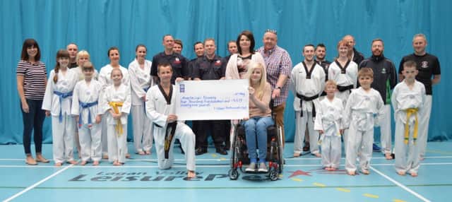 Members of Lisburn Taekwondo and local firefighters who raised money for crash victim Anastassiya, present a Â£4,479 cheque to the teenager and her family.