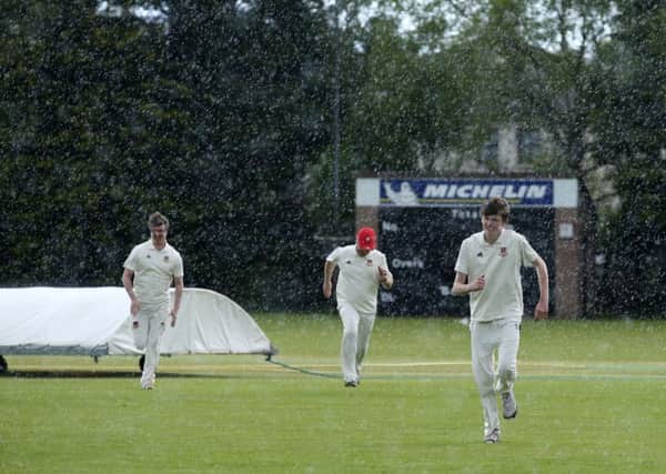 The joys of cricket in an Ulster summer as Ballymena players run for shelter after putting on the covers during Saturday's league game with Woodvale. INBT 21-189CS