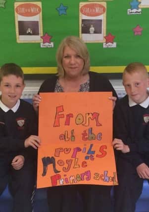 Moyle Primary School P5 pupils Cody Perry (left) and Deon Marcus present Northern Ireland player Gareth McAuley's mum Mildred with a good luck card for the Euros. INLT-22-706-con