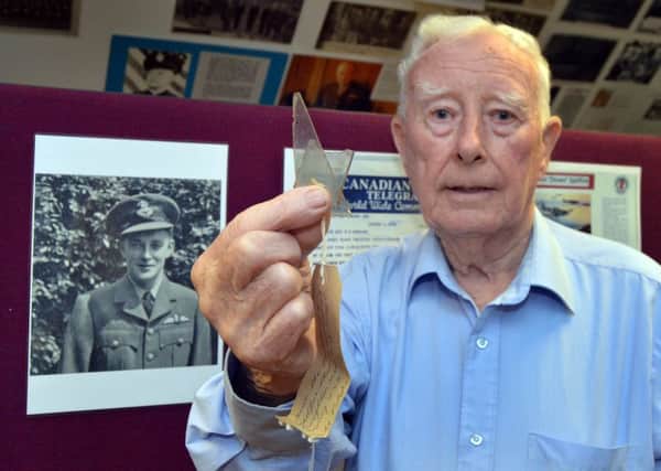 Tom Matthews with the piece of a crashed spitfire he salvaged during WWII near Derrymacash. In the background is a photo of the pilot who died. INLM23-202.