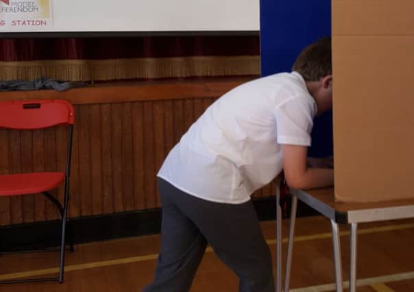 A pupil casts his vote in Model Primary School's EU Referendum. INCT 25-709-CON