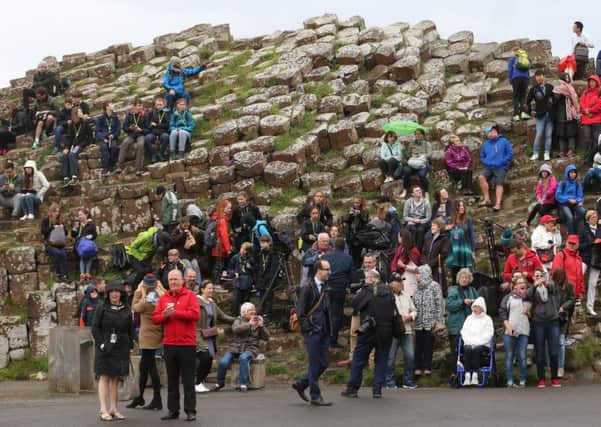 Tourists await the arrival of the Queen Elizabeth II and the Duke of Edinburgh to the Giant's Causeway on the Co Antrim coast during the second day of her visit to Northern Ireland to mark her 90th birthday. PRESS ASSOCIATION Photo. Picture date: Tuesday June 28, 2016. See PA story ROYAL Ulster. Photo credit should read: Niall Carson/PA Wire