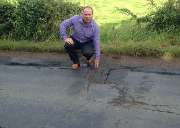 Sinn Fein Cllr Fergal Lennon inspects the cracks which have appeared on one of the many roads across the borough