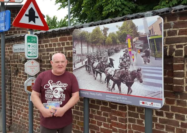 Ballymena man Bobby Allen with the poster in Poperinge. His grandfather is one of the men in this photograph. Pic Kenny Allen