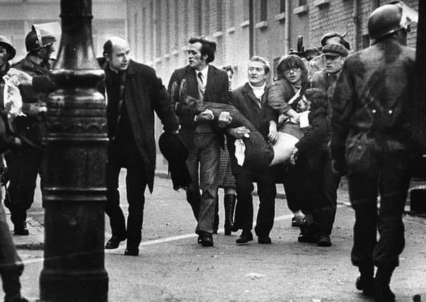 Bishop Daly helps clear a path for a man badly injured during Bloody Sunday in Londonderry