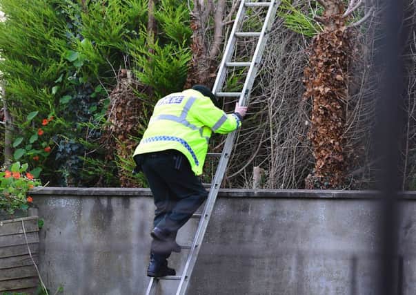An officer on a ladder near the crime scene on Tuesday morning
