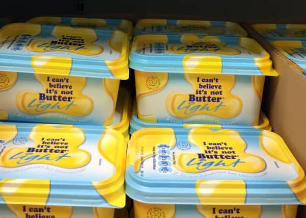 Tubs of 'I can't believe it's not butter' on a shelf in a Tesco store