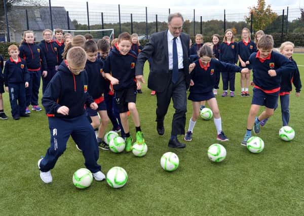 Education Minister, Peter Weir, shows of some of his footballing skills with pupils of Orchard Primary School Annaghmore at the official opening of the school's new MUGA pitch last week. INPT43-201.