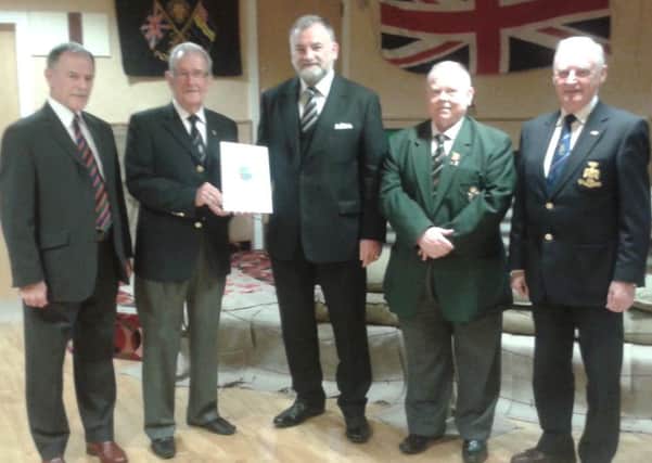 Manager of Joseph Poots and Son, Ellison Sloan (middle) presents a copy of a recipe book Lest We Forget to members of the British Legion
