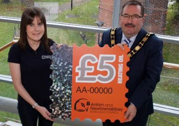 Mayor of Antrim and Newtownabbey, Councillor John Scott is joined by Kelly Forsythe, Environmental Health Officer to promote the Oil Stamp Saving Scheme.