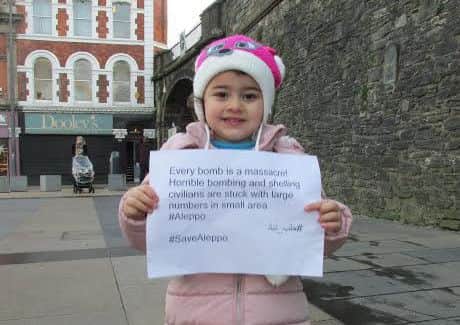 One of the little Syrian children who have been re-settled in Londonderry holds up a poster at the protest on Tuesday afternoon. (Picture by Frankie McMenamin)