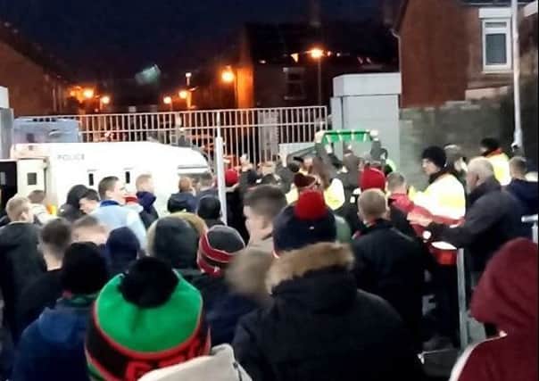 Stand-off: Glentoran supporters react to provocation from outside the ground as they try to exit Windsor Park after their team's Boxing Day game against Linfield. A green recycling bin can be seen flying over the fence towards the crowd - one of a number of items thrown during the disturbance.