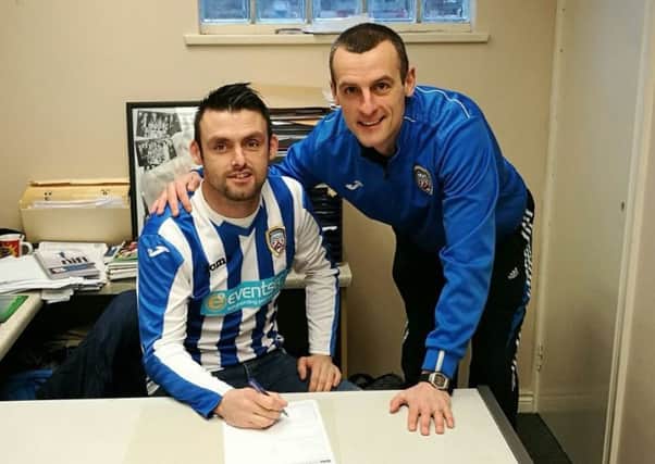 Eoin Bradley puts pen to paper on a two-and-a-half year deal with Coleraine as boss Oran Kearney looks on.