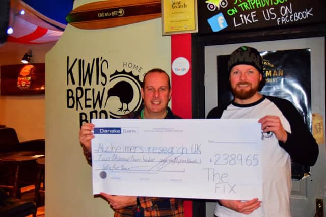 Jonny Lennox, frontman of The Fix, and Kris Charteris, owner of Kiwis Brew Bar, display a cheque for Alzheimers Research UK following the bands 25-year charity reunion night