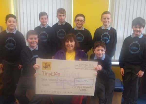 Glynn PS P7 pupils present a cheque for Â£320 to Gillian Breen of TinyLife.