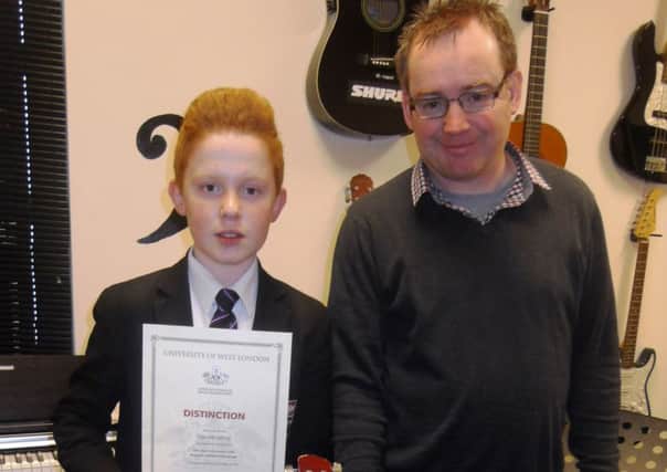 New-Bridge Tom McCaffrey year 9 on who achieved a Distinction in guitar. Looking on is tutor, Mr Michael Murphy