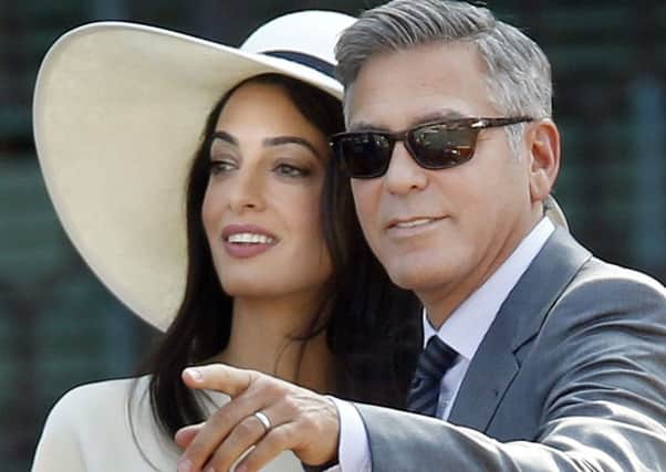 George Clooney, right, flanked by his wife Amal Alamuddin, arrives at the Cavalli Palace for the civil marriage ceremony in Venice, Italy, Monday, Sept. 29, 2014. George Clooney married human rights lawyer Amal Alamuddin Saturday, the actor's representative said, out of sight of pursuing paparazzi and adoring crowds. (AP Photo/Luca Bruno)