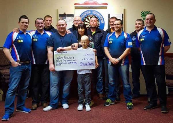 Jack Roycroft and his family receive a cheque for  Â£4011.95 which was raised by the Mechanics Institute Darts Team who organised a charity darts event for the youngster who is currently fighting kidney cancer