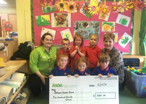 Principal Karen Castles and Ballyclare Nursery children receive the Â£500 cheque from Claione Alderdice (Asda Ballyclare Community Champion).