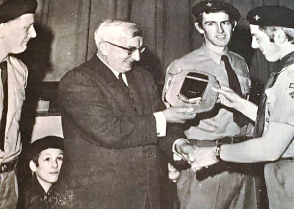 Patrol leader John Elliot of Second Lisburn Scout group (Wallace High School) presents Mr TCC Adam with a plaque to mark his retirement as headmaster in 1969. Also included is Mr Billy McKelvery, Scoutmaster and Mervyn French, assistant Scoutmaster