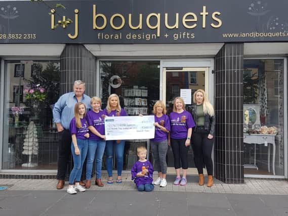 Heather's family and friends present the cheque to the Meningitis Research Foundation outside her shop.