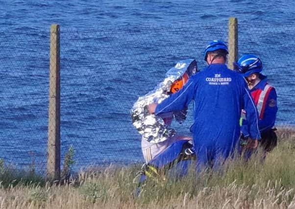 Coastguard officers lend a helping hand to the soaked and exhausted 16-year-old girl from the Ballymoney area, just after they hoisted her up a 100ft cliff to save her from the spring tide at Castlerock.