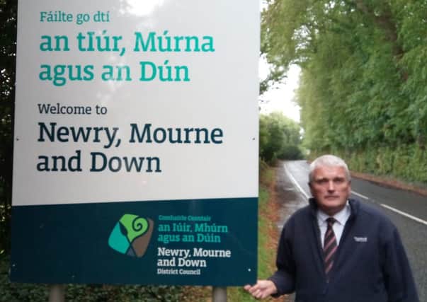 DUP MLA Jim Wells with the Newry and Mourne Down District Council boundart sign at Ballyward, Co Down, which has been destroyed and replaced four times since last year.