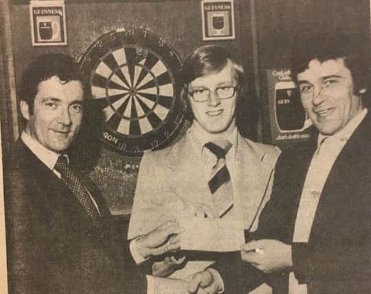 Damien Grimley (right) representative of Guinness, presents a sponsorship cheque for Â£100 for the Guinness Darts League to Brian McKernan, secretary of the league, and Gerone McCann, chair of the league in 1978.