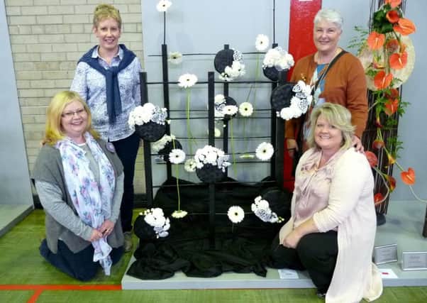 Four of Ballymena Floral  Art Group's talented ladies who excelled in NIGFAS competitions at Parkhall College: Standing L-R Julie Carlisle, Janet Wilson (Chairman), Kneeling L-R Colleen Hamill, Heather Hume. The ladies are pictured with The Belminster Class Entry (Striking a Different Note) by Julie and Colleen.